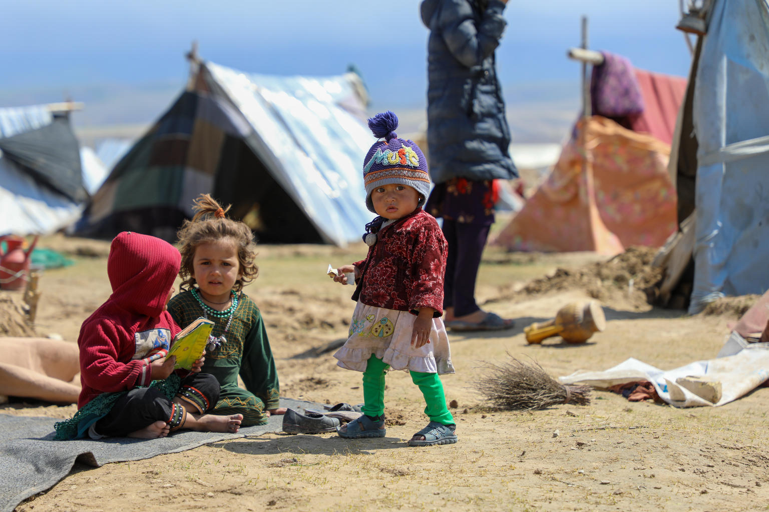 3 kids (2-3 years old) wearing winter cloth, in a camp setting