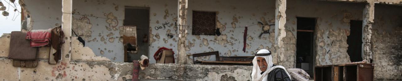 a man walking in the debris of bulleted buildings 