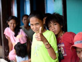 A Philippino woman gives a thumbs-up to the camera