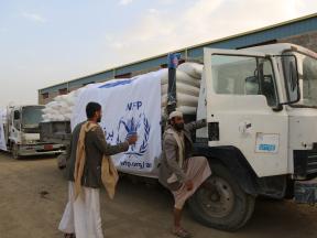 Two men climb into a WFP truck carrying sacks